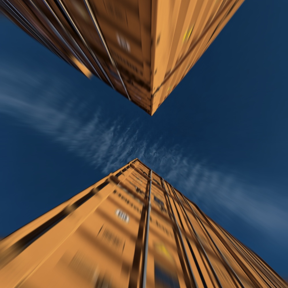 Stacked shipping containers seen from below against a blue sky