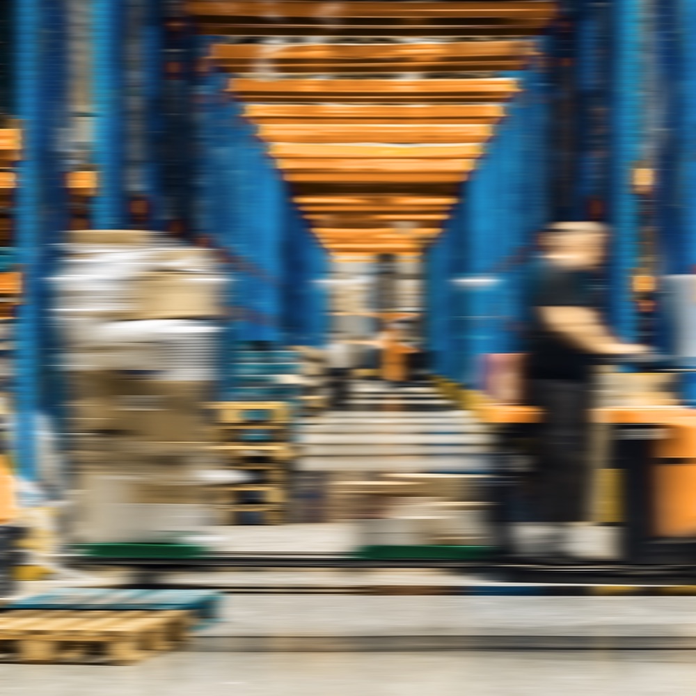 A warehouse aisle with racking, motion blurred